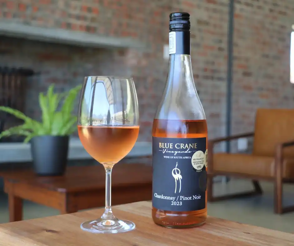 Blue Crane Vineyards — a bottle of Blue Crane Chardonnay / Pinot Noir and a filled glass on a table in the tasting room