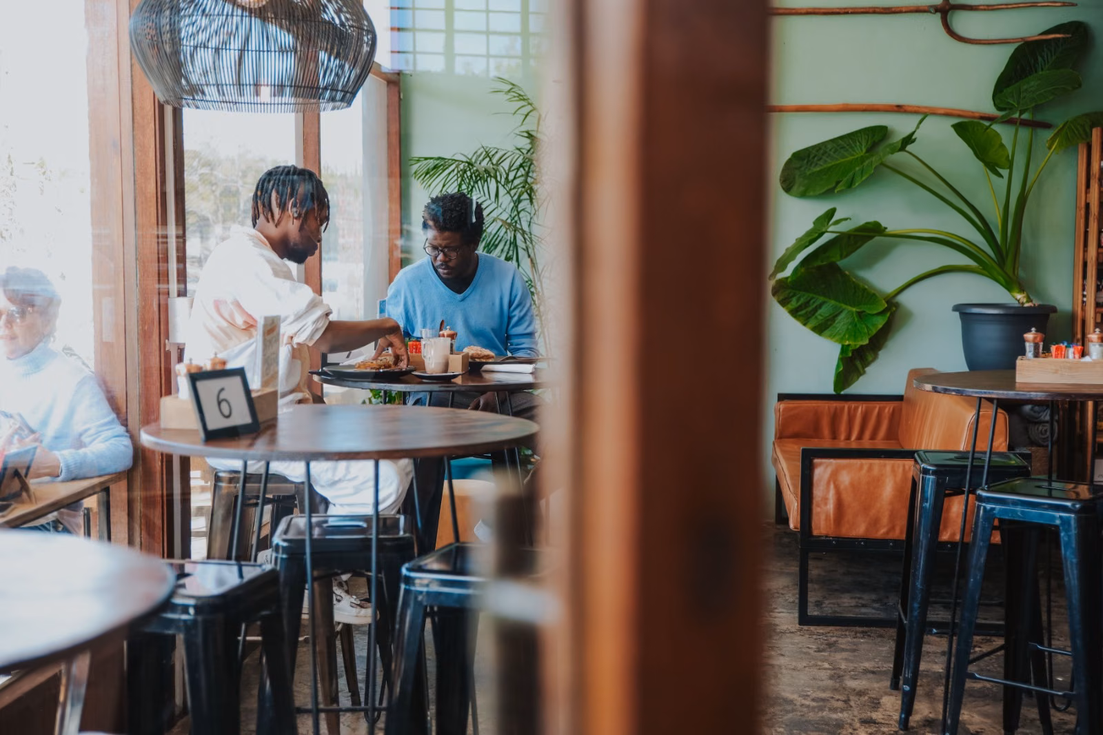 Kole & Deeg — guests at the café's window tables beside potted greenery