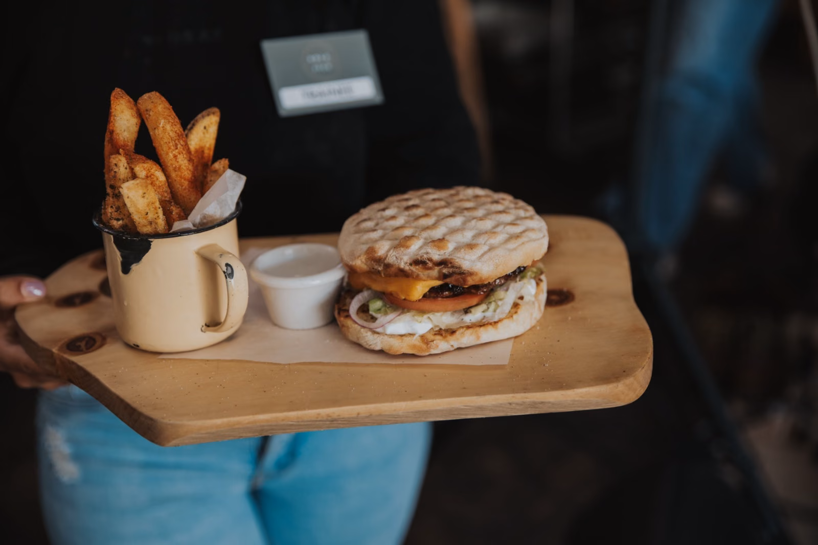 Kole & Deeg — a burger and a mug of thick-cut chips carried out on a wooden board