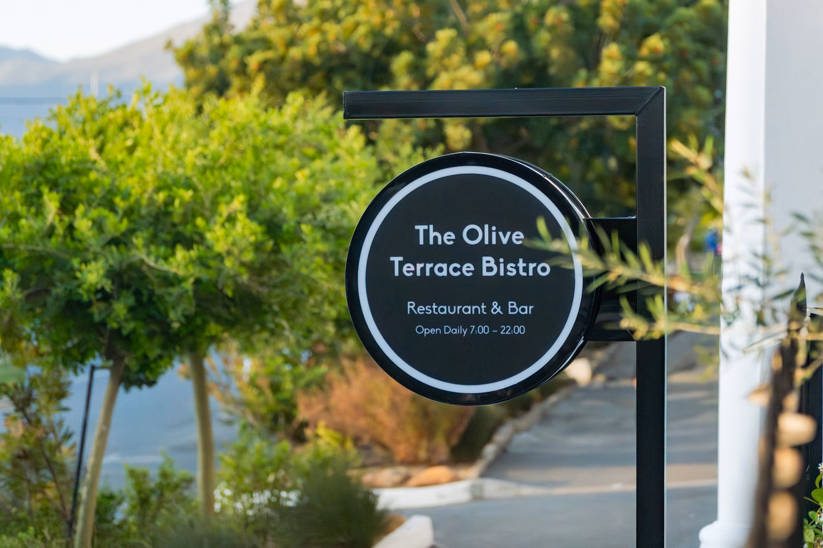 The Olive Terrace Bistro — the round street sign reading Restaurant & Bar, open daily 7.00–22.00